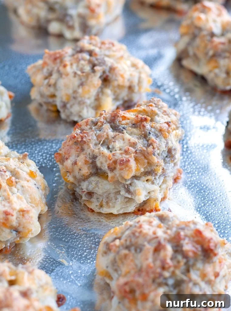 Easy sausage ball recipe Freshly baked Bisquick Sausage Balls arranged neatly on a parchment-lined baking sheet, golden brown and ready to be served.