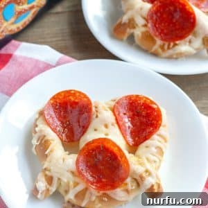 Plate with a delicious soft pretzel pizza topped with pepperoni and cheese.