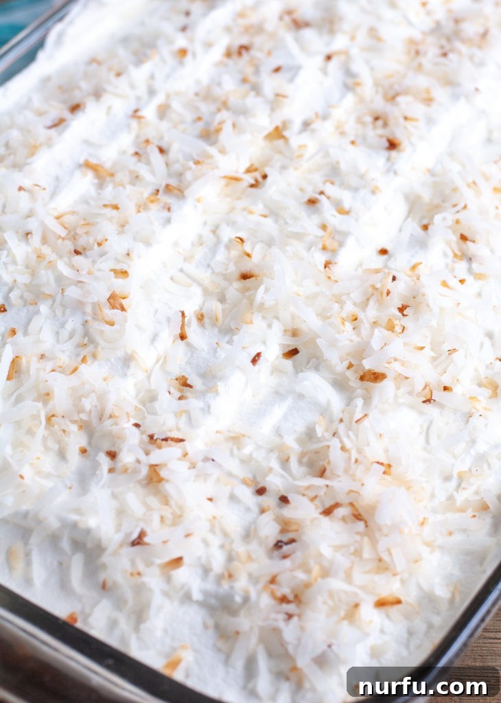 Orange Poke Cake Topped with whipped topping and toasted coconut