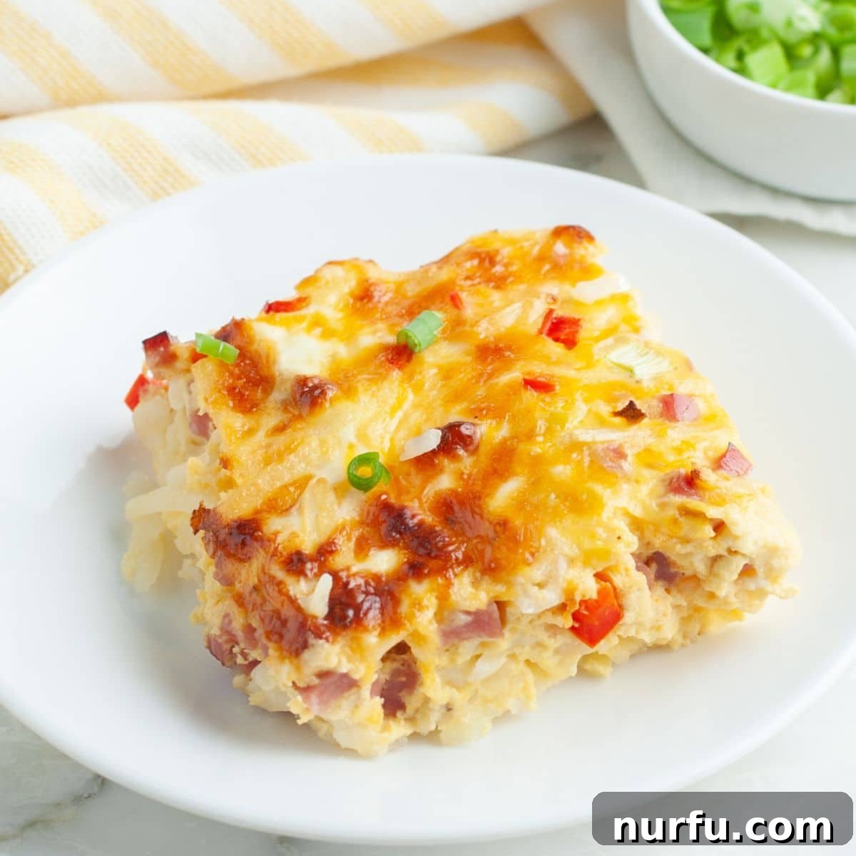 Hearty Farmhouse Casserole 7 A perfectly baked Farmers Casserole, golden brown and bubbly, showcasing a slice on a white plate, ready for a delicious breakfast.
