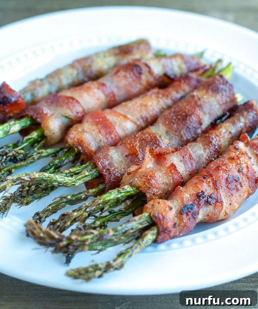 Air Fryer Bacon Wrapped Asparagus Air Fryer Bacon Wrapped Asparagus on a white plate, showcasing crispy bacon and green asparagus
