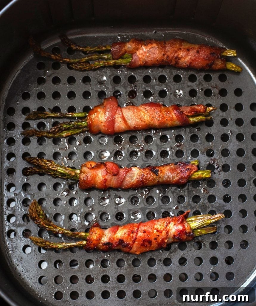 Air Fryer Bacon Wrapped Asparagus Cooked Air Fryer Bacon Wrapped Asparagus in the air fryer basket, golden and crispy