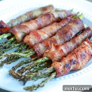 Crispy Air Fryer Bacon Wrapped Asparagus 2 Bacon wrapped asparagus on plate.