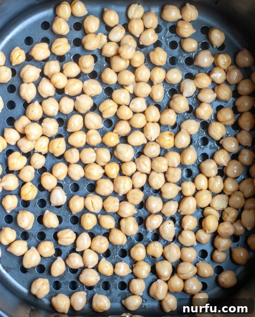 Air Fryer Roasted Chickpeas Seasoned chickpeas spread in a single layer in an air fryer basket.