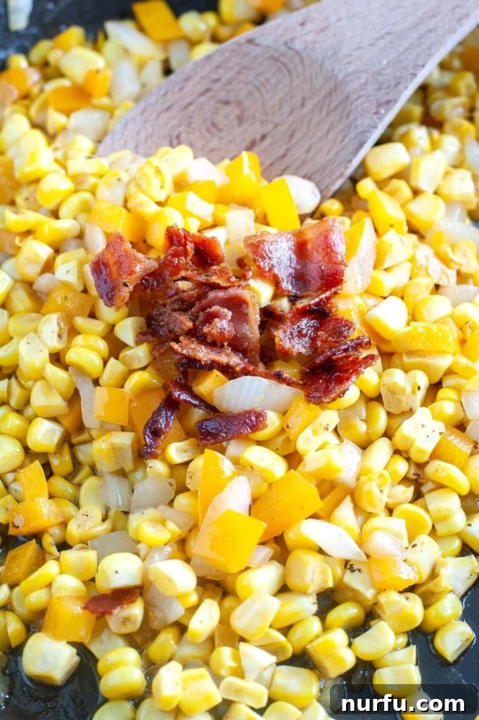 Fried Corn A skillet full of delectable Southern fried corn topped with crumbled crispy bacon, with a wooden spoon nestled within, ready to be served