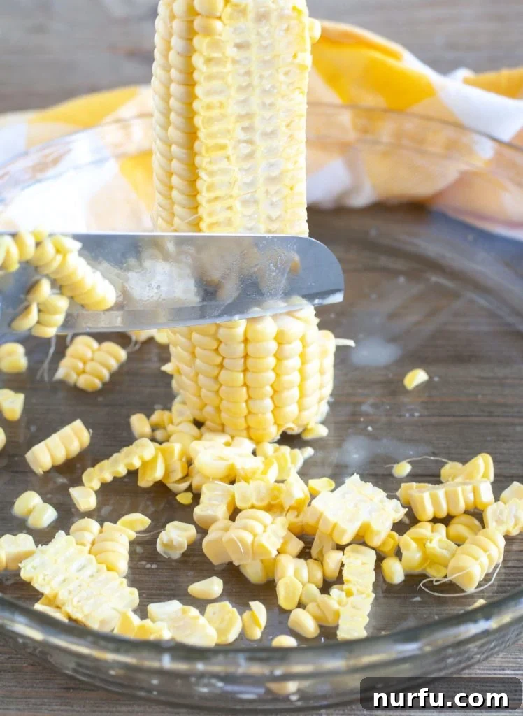 Fried Corn An ear of corn standing upright in a pie plate, with a knife carefully slicing off corn kernels, demonstrating an effective method for preparation