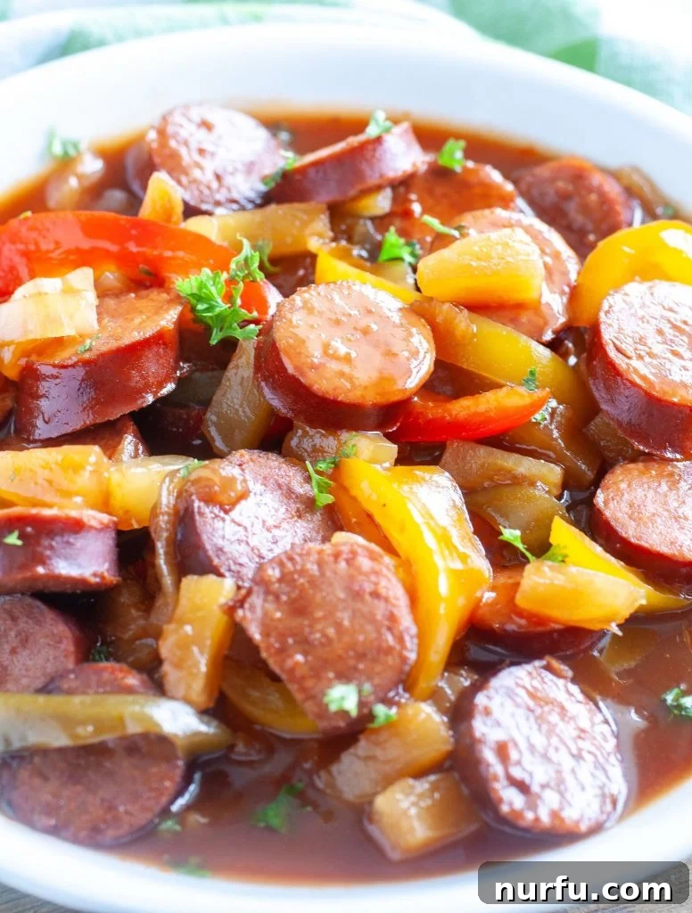 Sweet and Sour Crockpot Kielbasa A delicious bowl of sweet and sour kielbasa with onions and peppers served over a bed of rice, garnished for a perfect family meal.