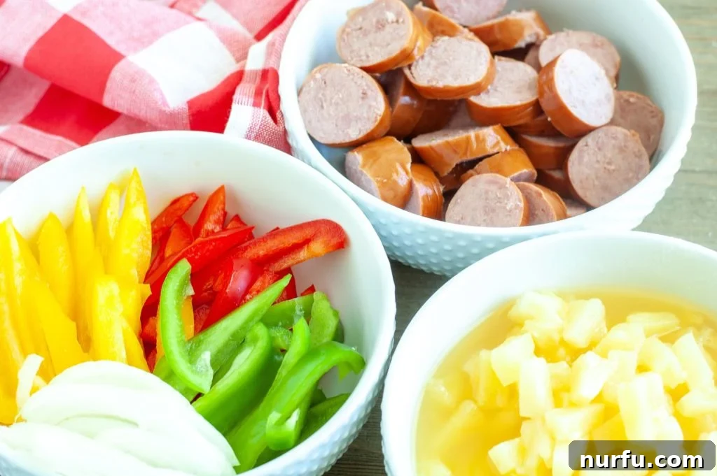 Sweet and Sour Crockpot Kielbasa A vibrant assortment of un-cooked ingredients for sweet and sour kielbasa including sliced kielbasa, colorful bell peppers, onions, and pineapple tidbits, ready for the crockpot.