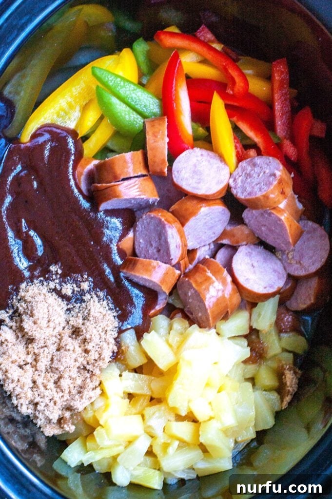 Sweet and Sour Crockpot Kielbasa Sliced kielbasa, colorful bell peppers, pineapple tidbits, and onions in a crockpot, coated in BBQ sauce and brown sugar, ready for slow cooking.