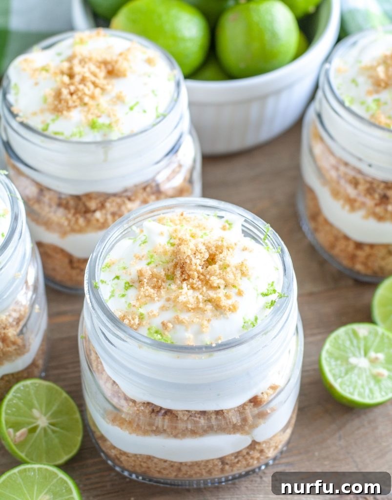 No Bake Key Lime Trifle Several individual Key Lime Trifles in small glass jars, beautifully layered and garnished. A bowl of fresh Key limes sits nearby.