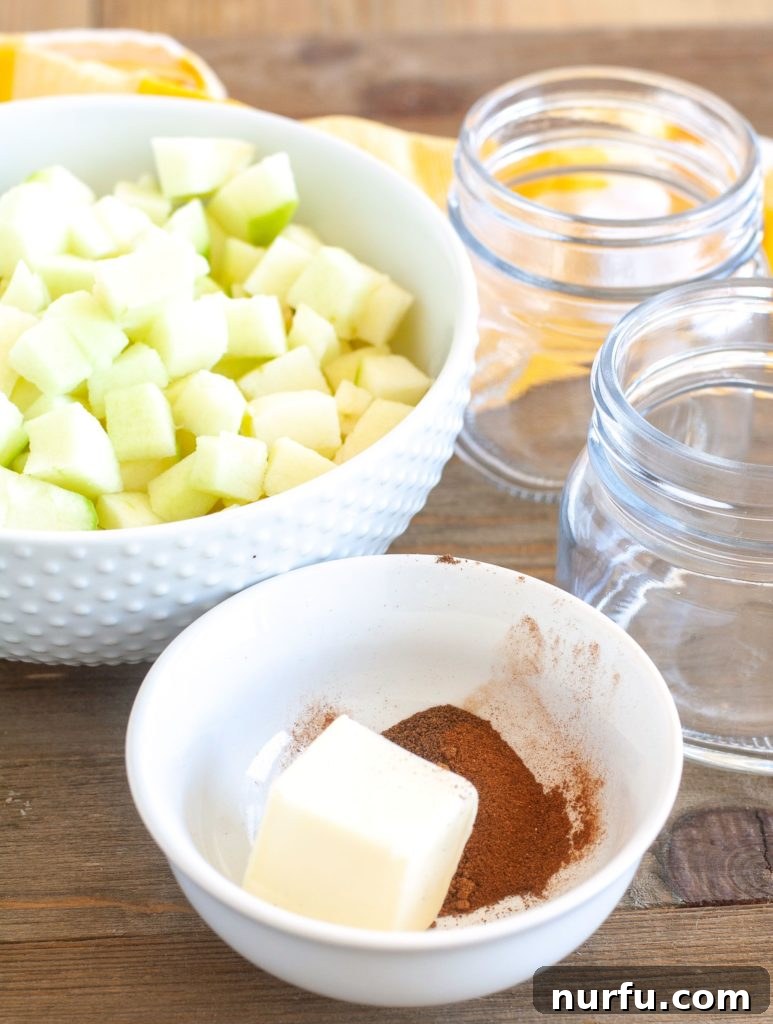 Apple Pie Filling Ingredients A vibrant display of fresh ingredients for apple pie filling: diced apples, butter, cinnamon, nutmeg, and allspice, alongside empty glass jars.