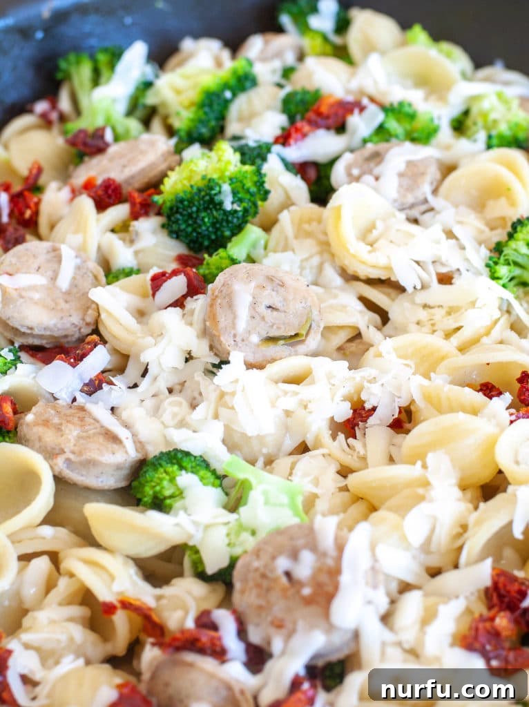 Orecchiette with broccoli A large skillet filled with Orecchiette pasta, chicken sausage, and broccoli, perfectly combined and ready to be served.