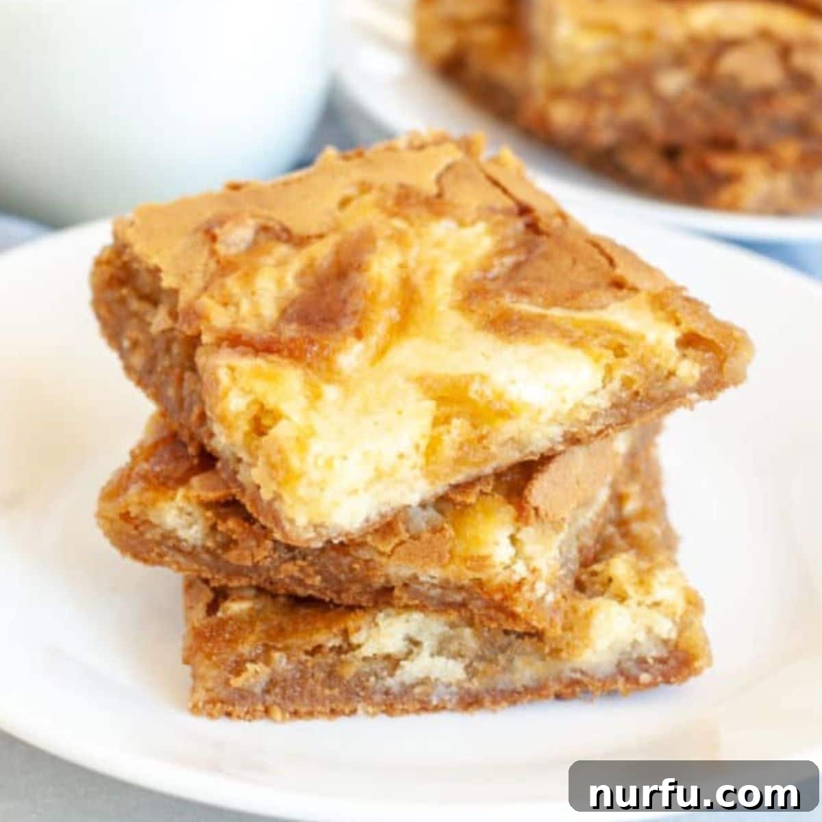 Creamy Swirl Blondies 2 Stack of cream cheese swirled blondies on a white plate