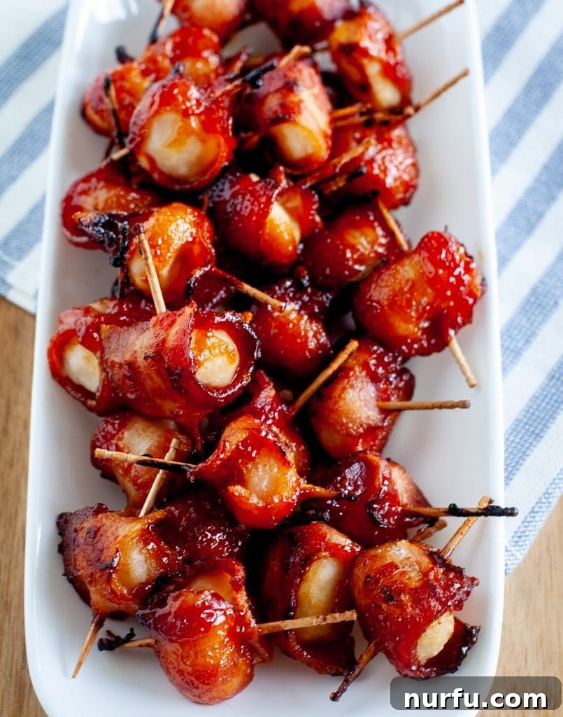 Crispy Bacon Wrapped Water Chestnuts 7 A white oval serving dish filled with perfectly baked bacon wrapped water chestnuts, ready to be enjoyed.