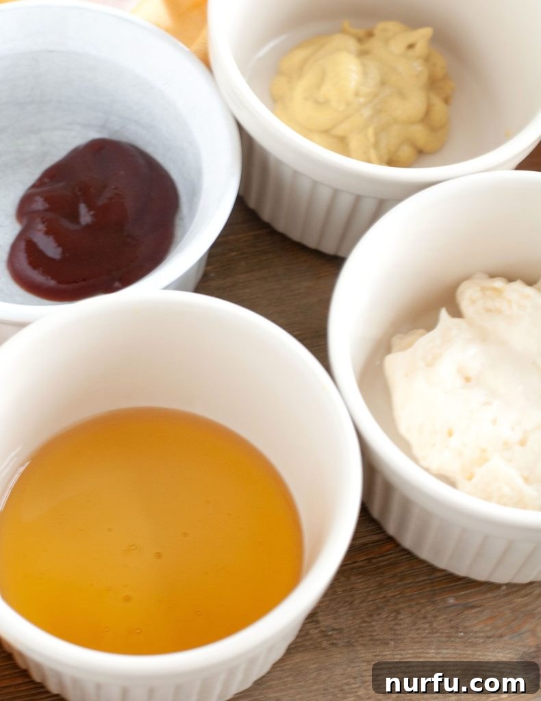 Air Fryer Honey Mustard Sauce Ingredients Individual bowls containing honey, brown mustard, BBQ sauce, and mayonnaise, showcasing the fresh ingredients for the homemade glaze.