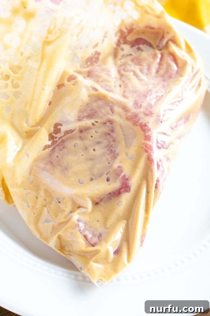 Pork Chops Marinating Boneless pork chops fully submerged and marinating in a vibrant honey mustard sauce inside a sealed zip-top bag.