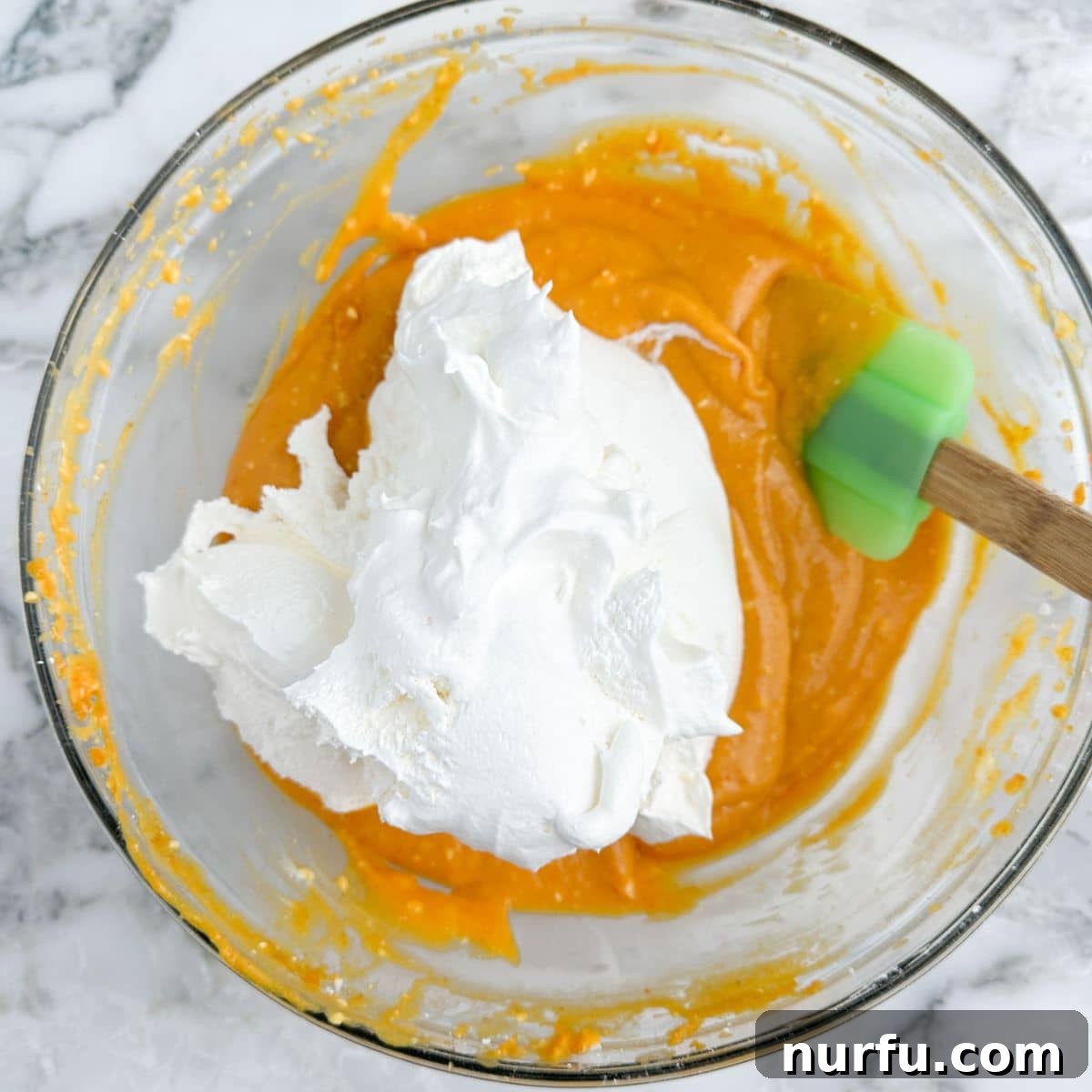 Velvety Pumpkin Spice Dip 6 A bowl containing the smooth pumpkin and cream cheese mixture, with a generous dollop of thawed Cool Whip on top, ready to be gently folded in to create a light and airy dip.