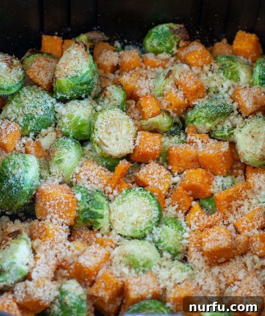 Air Fryer Roasted Parmesan Brussels Sprouts and Squash Side Dish Crispy Air Fryer Roasted Parmesan Brussels Sprouts and Butternut Squash in an air fryer basket, ready to serve, showing golden cheese and caramelized edges.