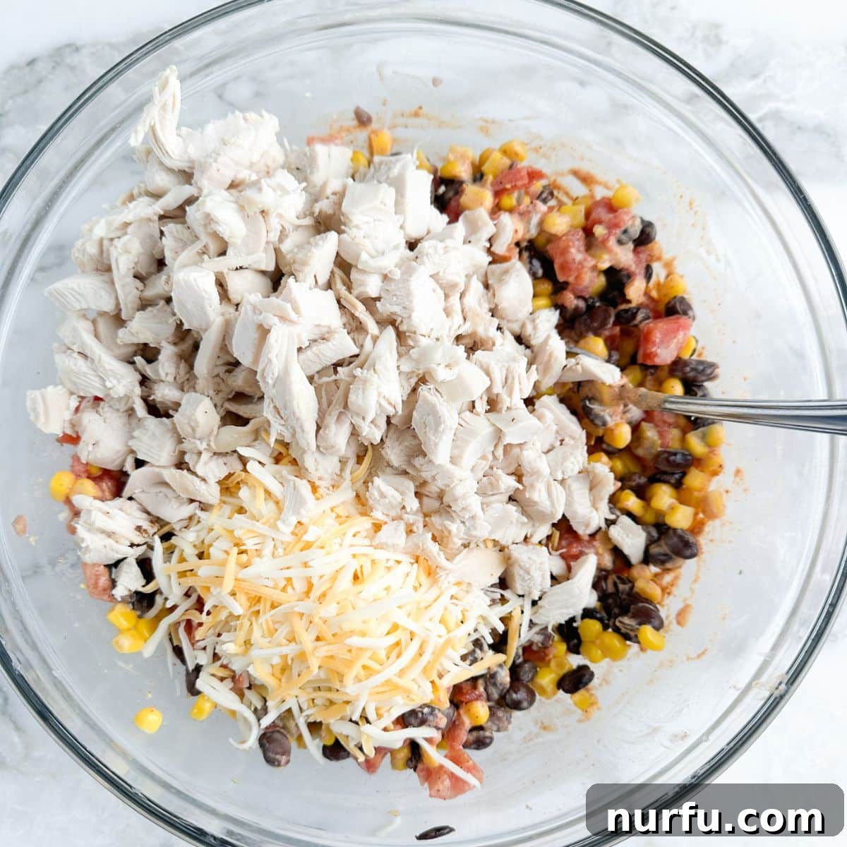 Celebration Chicken Bake 5 Bowl with bean mixture, diced chicken, and shredded cheese ready to be mixed.
