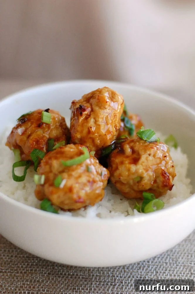Sticky Pineapple Teriyaki Chicken Meatballs 2 Delicious chicken teriyaki meatballs glazed in a savory sauce, served over rice with a sprinkle of green onions.