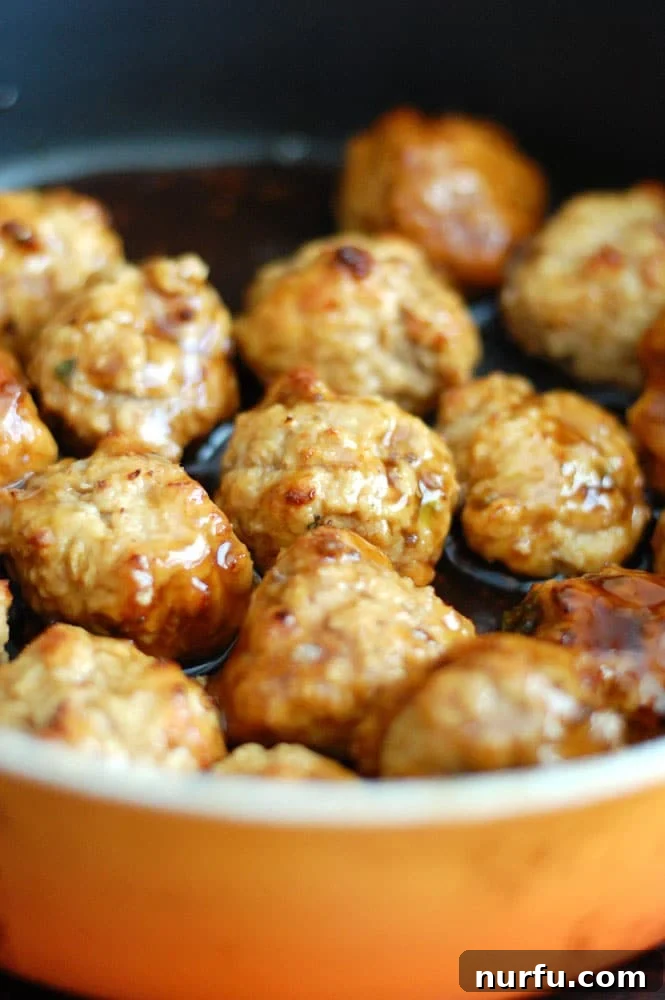 Sticky Pineapple Teriyaki Chicken Meatballs 5 A vibrant bowl of chicken teriyaki meatballs served on white rice, garnished with fresh green onions, showcasing a delicious homemade meal.