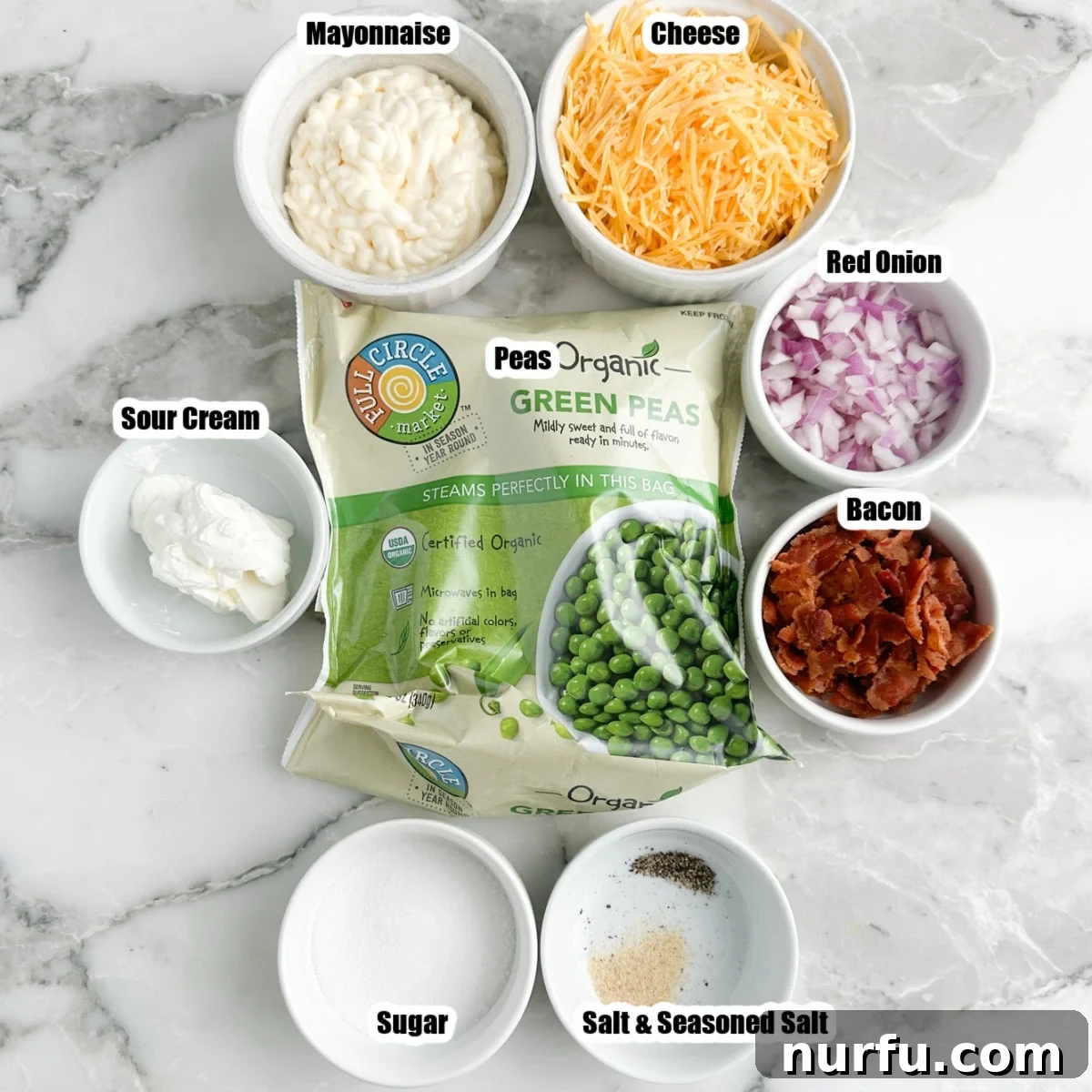 Quick and Creamy Pea Salad 2 Individual bowls containing a bag of frozen peas, shredded cheese, mayonnaise, sour cream, cooked bacon crumbles, and finely diced red onions, showcasing the fresh ingredients for pea salad.