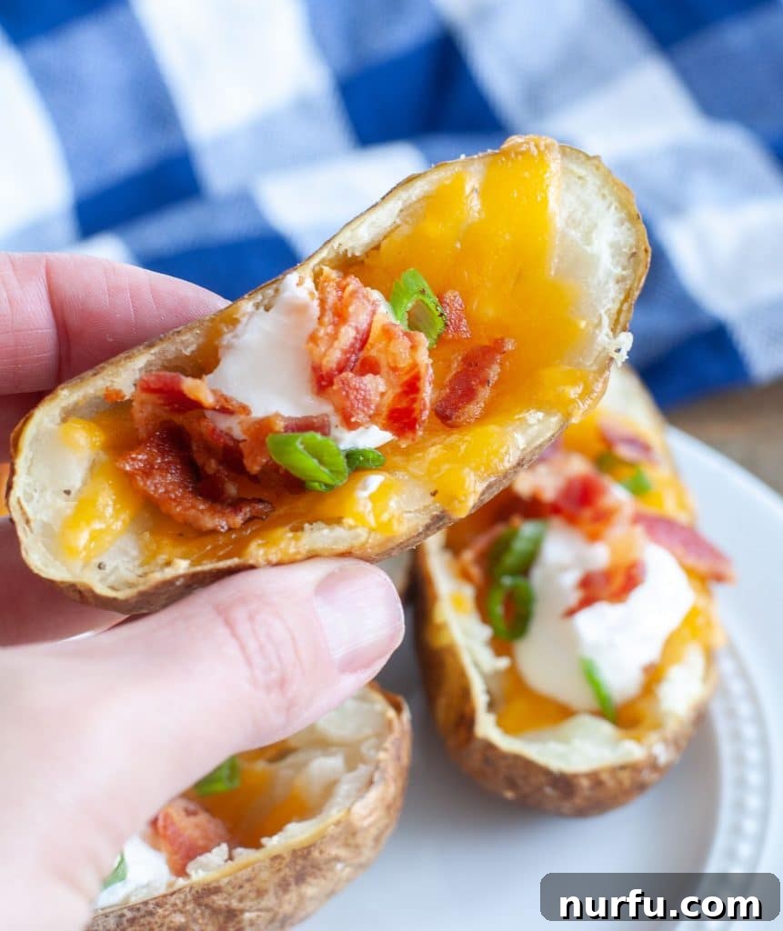 Ultimate Air Fryer Potato Skins 5 Hand holding an air fried potato skin with cheese, bacon and sour cream