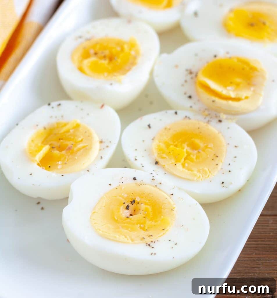 Air Fryer Eggs Made Easy 2 Air Fryer Hard Boiled Eggs cut in half on a white plate, showing perfectly cooked yolks