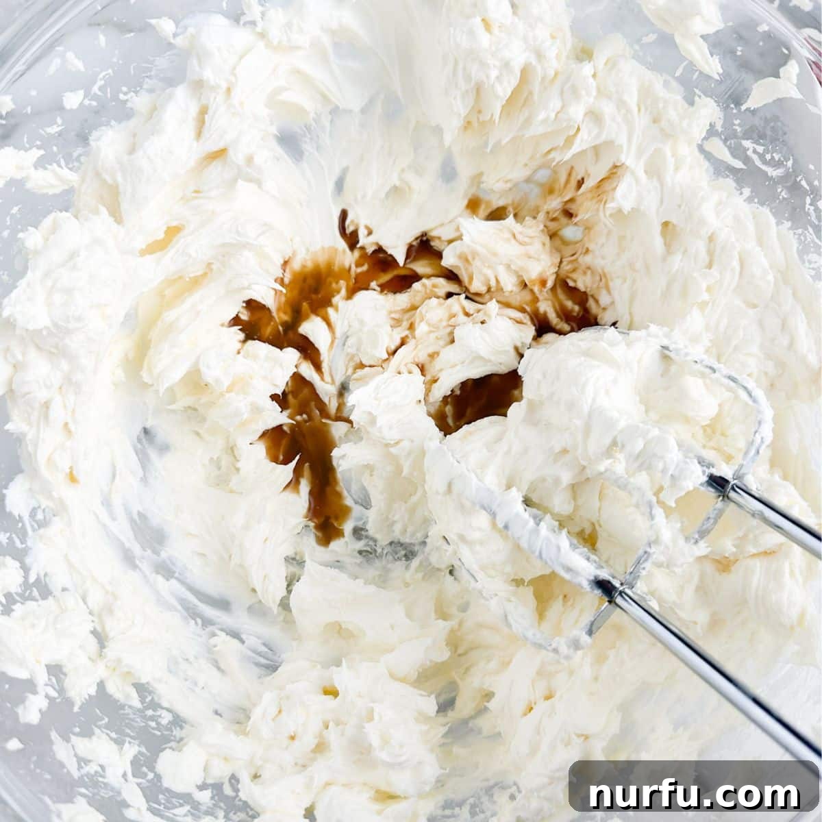 A large mixing bowl containing softened cream cheese, sour cream, garlic powder, and a generous swirl of Worcestershire sauce, ready to be blended into a smooth, savory dip base.