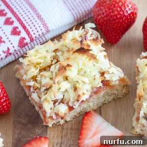 Tropical Strawberry Coconut Bars 4 A perfectly cut strawberry bar square with a fresh strawberry beside it, ready to be served