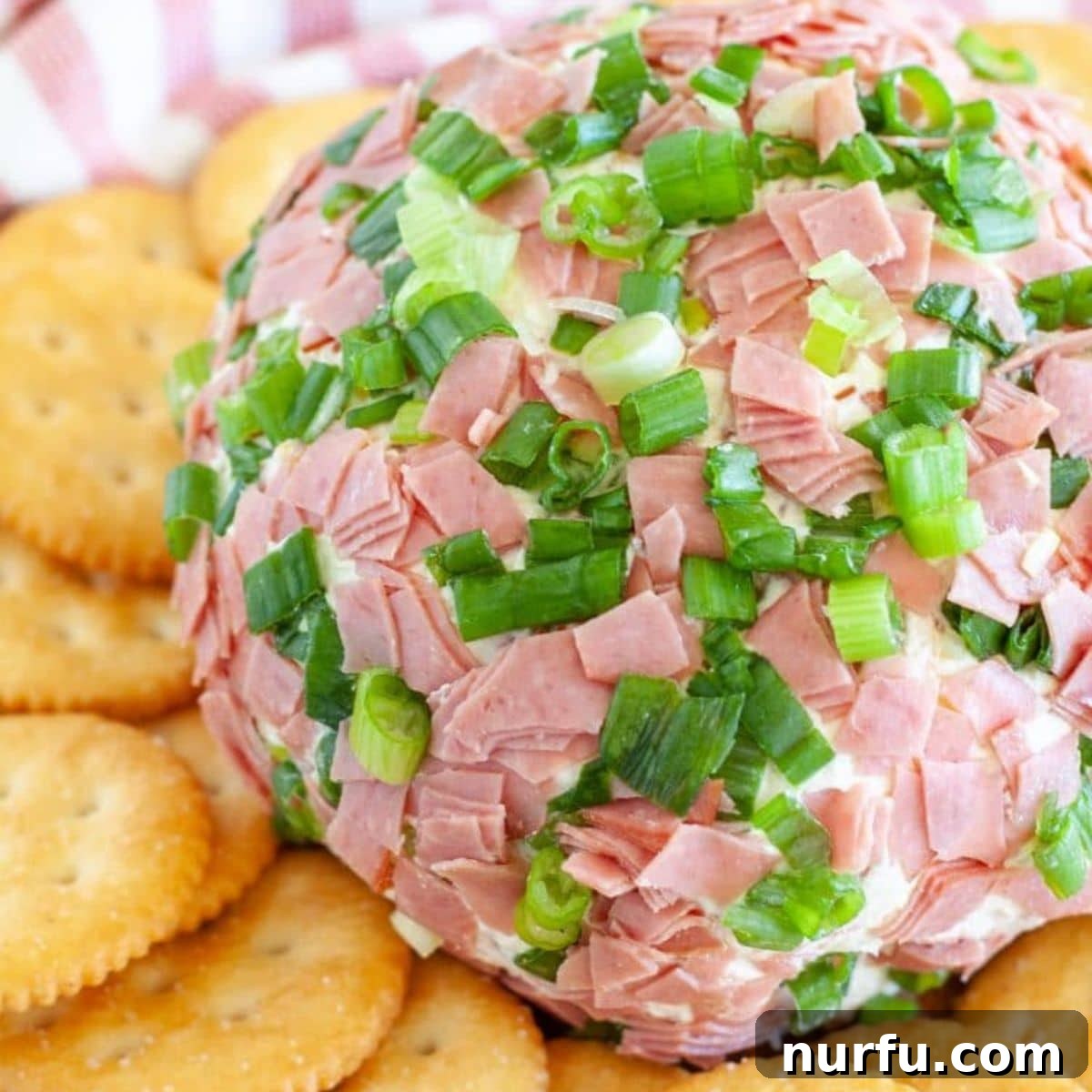 Signature Chipped Beef Cheese Ball 2 A classic Chipped Beef Cheese Ball appetizer, garnished with green onions and served with an assortment of crackers on a wooden board. Perfect for holiday gatherings.