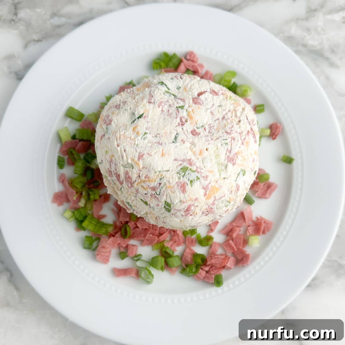Signature Chipped Beef Cheese Ball 8 A Chipped Beef Cheese Ball beautifully coated with finely chopped chipped beef and green onions, presented on a plate.