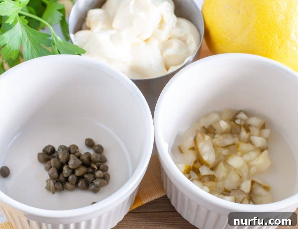 Homemade Creamy Tartar Sauce 3 Fresh ingredients laid out for tartar sauce: capers, pickles, lemon, mayonnaise, and parsley.