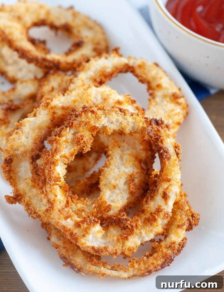 Crispy Air-Fried Onion Rings 2 Golden brown air fryer onion rings piled on a plate, ready to be served.