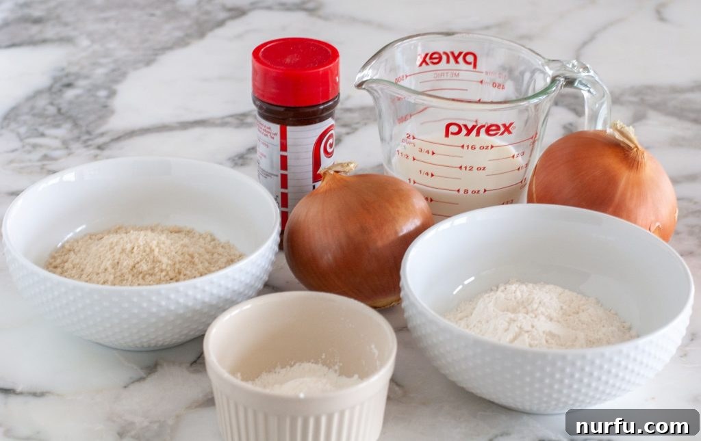 Crispy Air-Fried Onion Rings 3 Bowls of raw ingredients for air fryer onion rings: flour, cornstarch, sliced onion, milk, seasoning, and panko breadcrumbs.