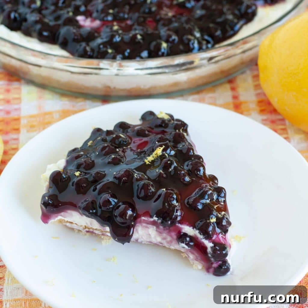 Blueberry Lemon Pie on a white plate, showcasing its creamy lemon filling, vibrant blueberry topping, and golden crumb crust. Perfect for a refreshing dessert.