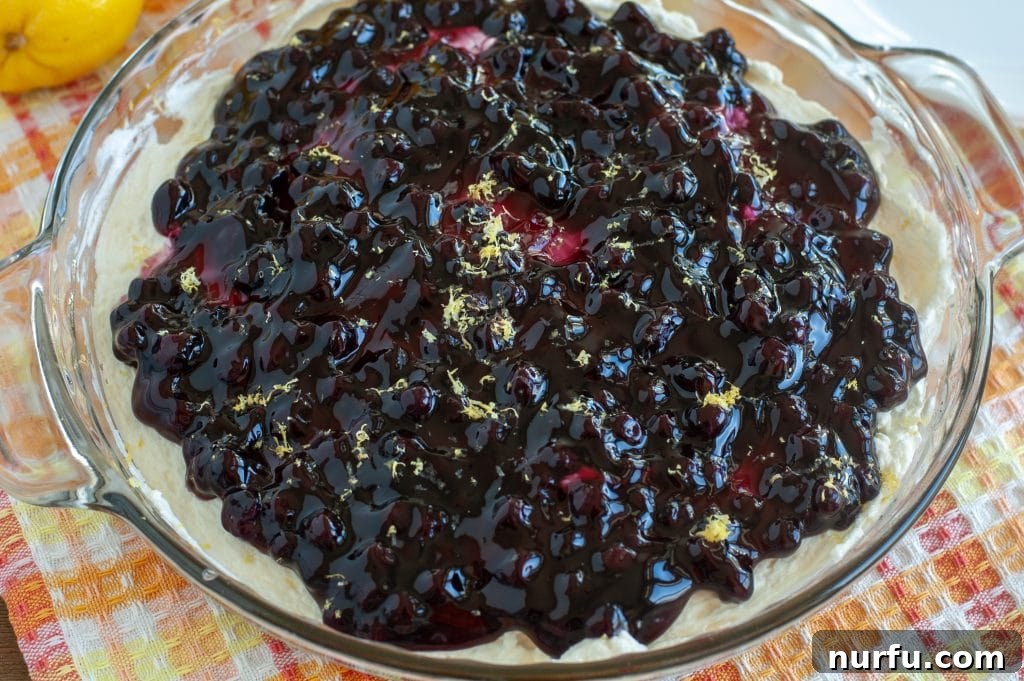 A beautifully set, whole Blueberry Lemon Crumb Pie resting in a glass pie dish, captured from an overhead angle, highlighting its vibrant colors and readiness for serving.