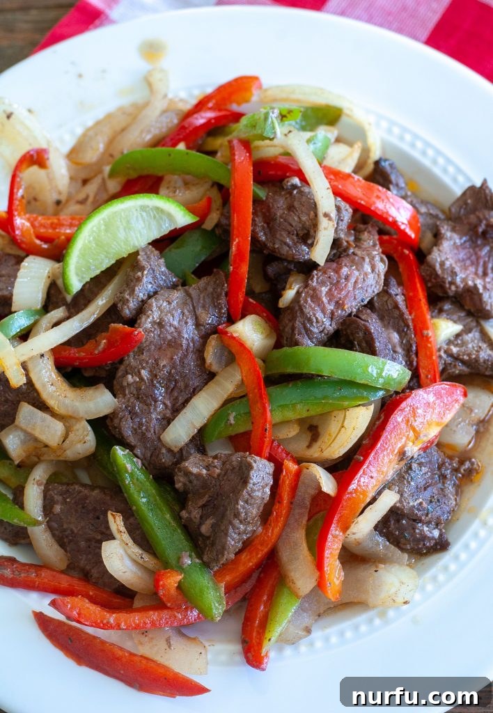 Delicious Air Fryer Steak Fajitas Plated Air fryer steak fajitas served on a white plate with bell peppers and onions, ready to be enjoyed.