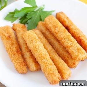 Crispy air fried fish sticks on a white plate with parsley garnish