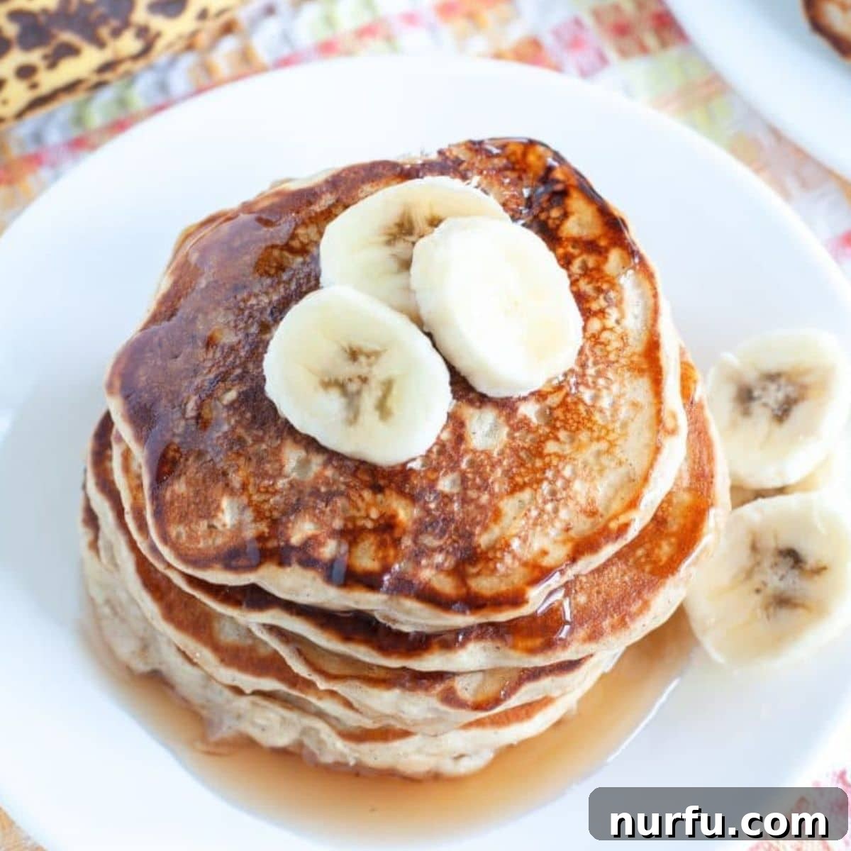 Wholesome Banana Oat Flapjacks 4 Stack of banana oatmeal pancakes with fresh banana slices and syrup, ready to eat.