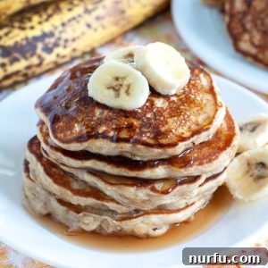 Banana Oatmeal Pancakes on a plate, garnished with fresh fruit and syrup