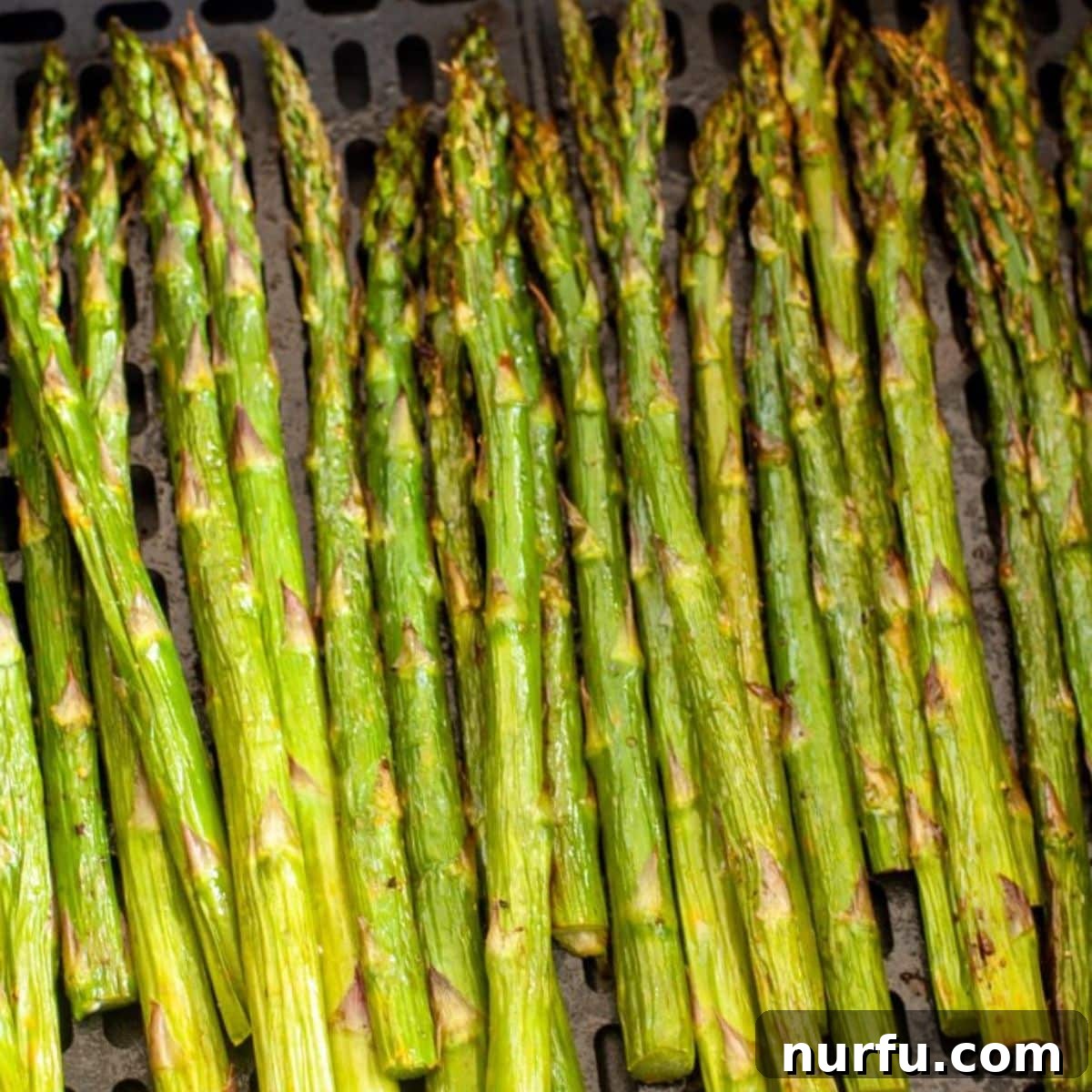Golden Air Fryer Asparagus 4 Close-up of perfectly cooked air fryer asparagus on a serving plate.