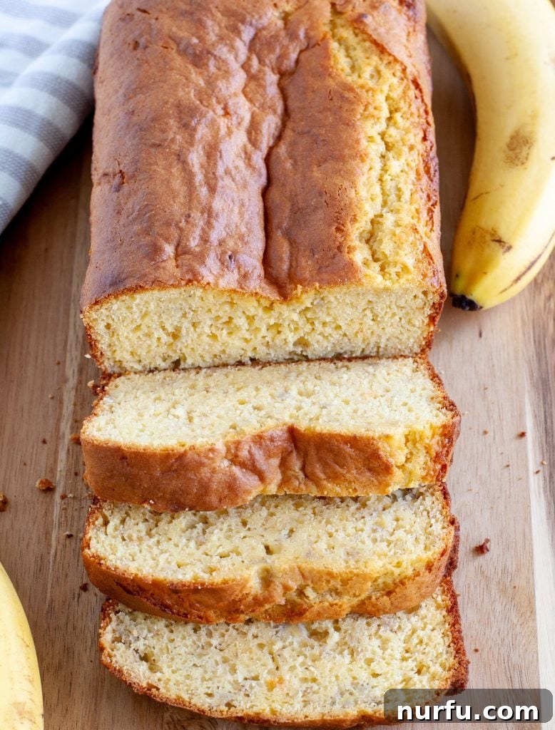 Easy Cake Mix Banana Bread 2 Deliciously moist cake mix banana bread slices on a wooden board, surrounded by fresh bananas, ready to be enjoyed as a breakfast or snack.