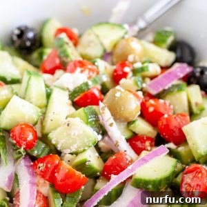 Refreshing Aegean Cucumber Medley 5 A vibrant Greek cucumber salad, featuring diced cucumbers, cherry tomatoes, red onion, crumbled feta cheese, and Kalamata olives, all tossed in a zesty lemon-oregano vinaigrette, served in a rustic ceramic bowl with a fork, ready to be enjoyed.