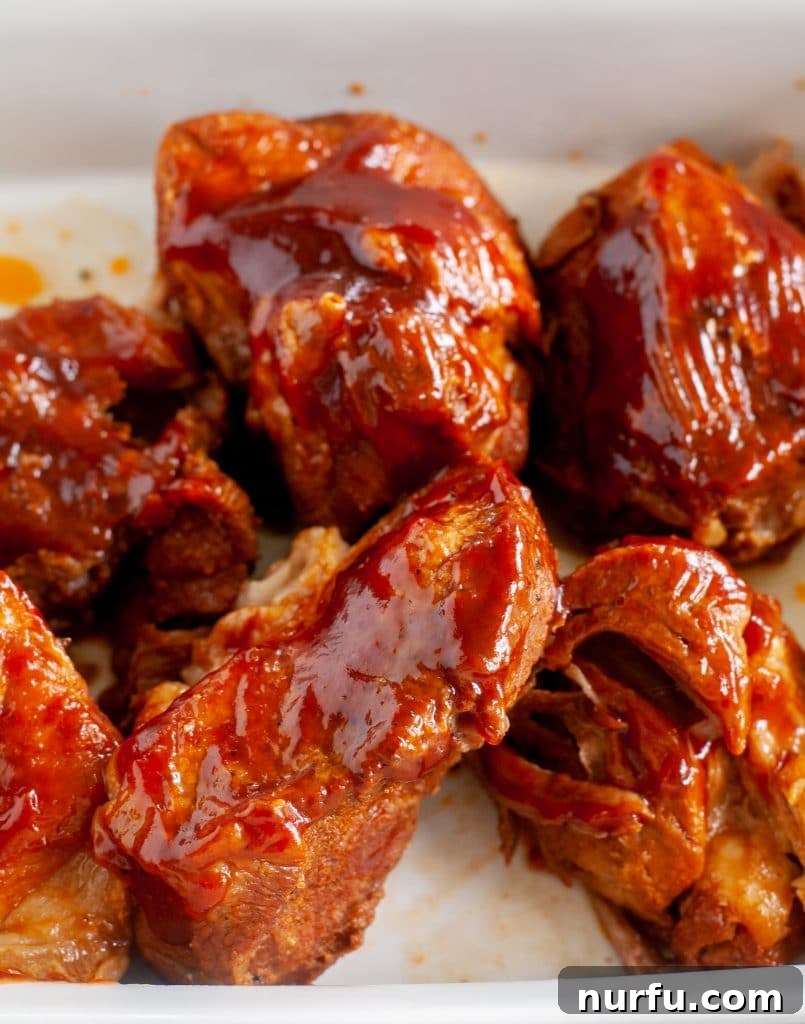 Fall-Off-The-Bone Instant Pot Country Ribs 5 Tender BBQ ribs with sauce in a casserole dish, ready for serving or reheating.