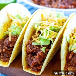 Three beef tacos on a plate with toppings, signifying a delicious meal.