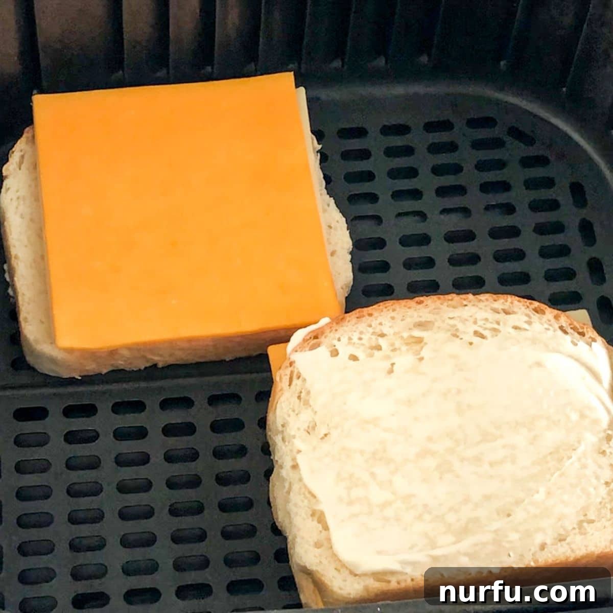 Crispy Air-Fried Cheese Toastie 4 Bread topped with butter and sliced cheese in an air fryer basket, ready for cooking.