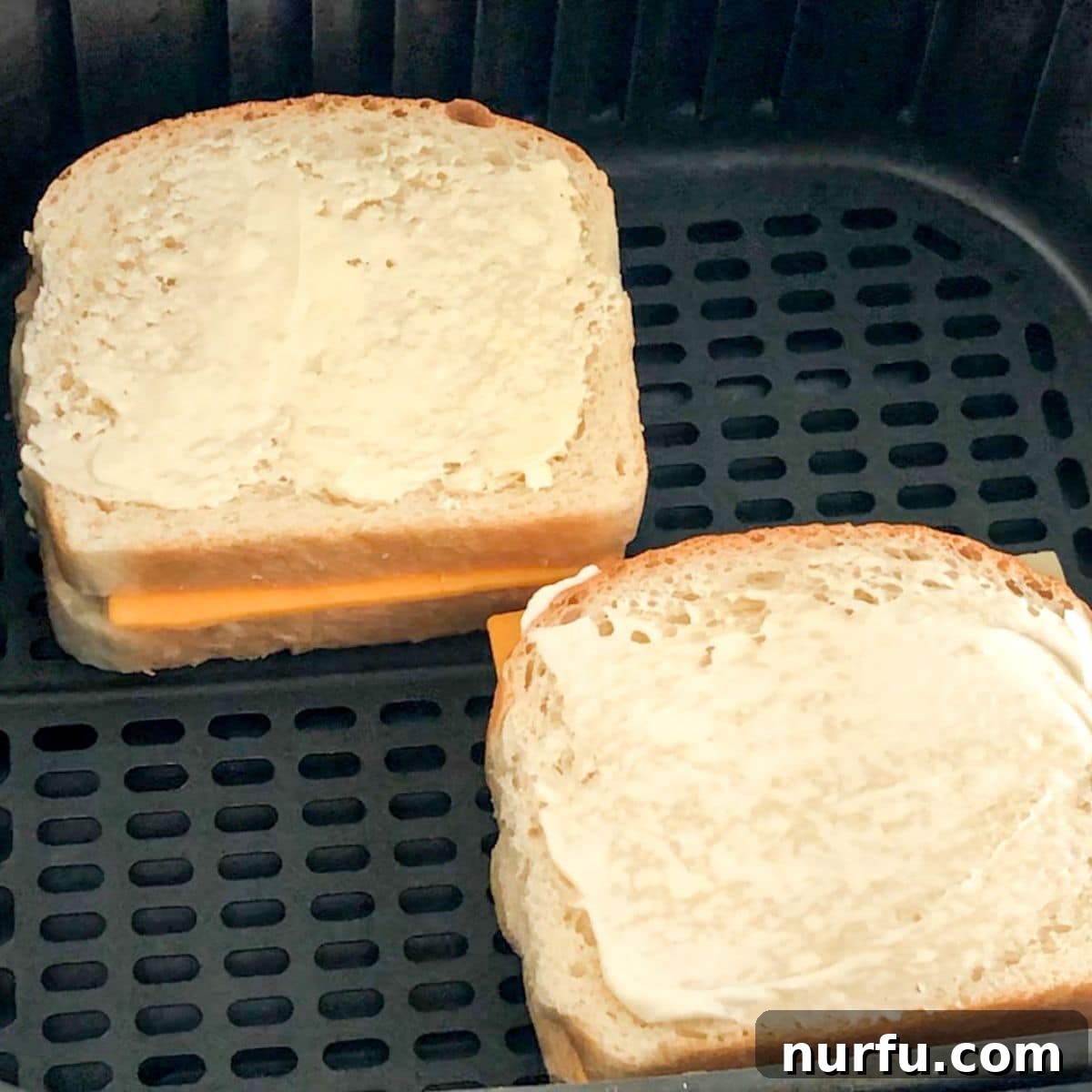 Crispy Air-Fried Cheese Toastie 5 Two uncooked grilled cheese sandwiches neatly arranged in an air fryer for cooking.