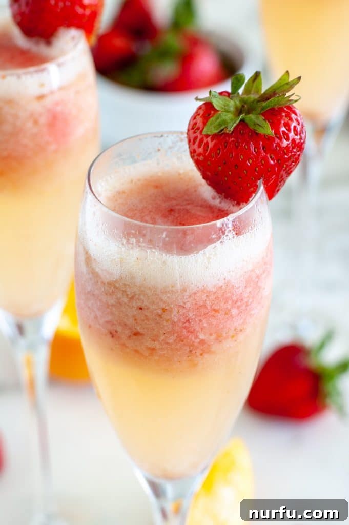 Glass with champagne and a strawberry garnish, showcasing a vibrant Strawberry Mimosa.