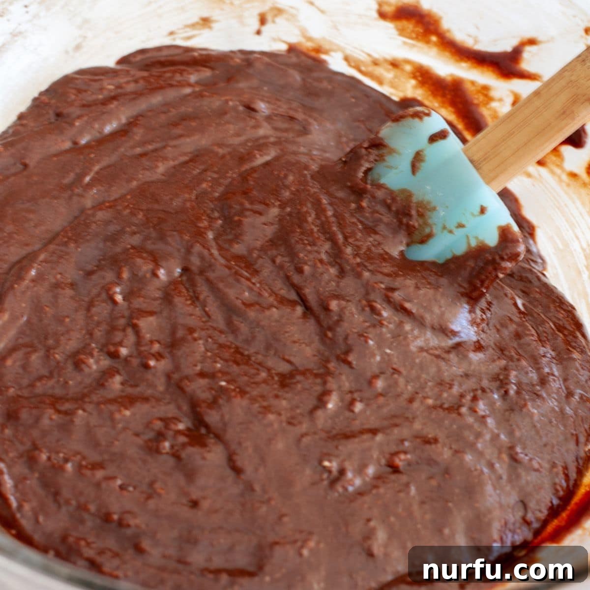 Coffee Kick Brownie Bites 3 Bowl of rich brownie batter being stirred with a spatula, showcasing its thick, fudgy texture.